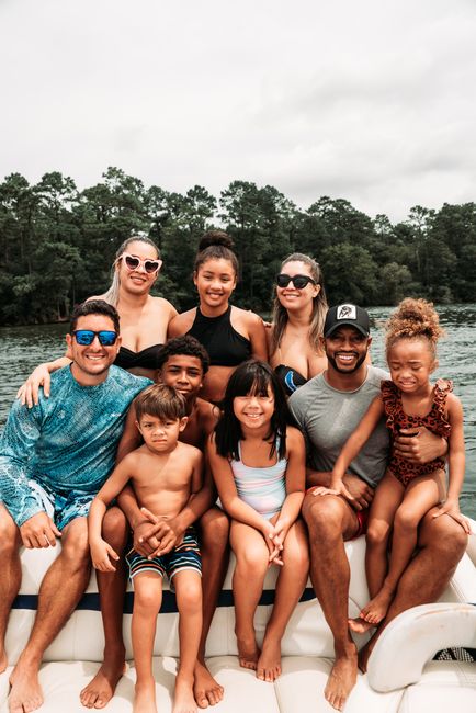 A joyful group of diverse family members smiling on a boat during summer in Houston, TX.